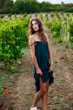 woman from the village in a green dress stands in a vineyard