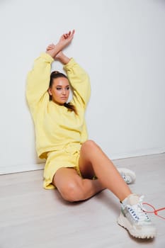 sporty woman in a suit sits on the floor with her hands up