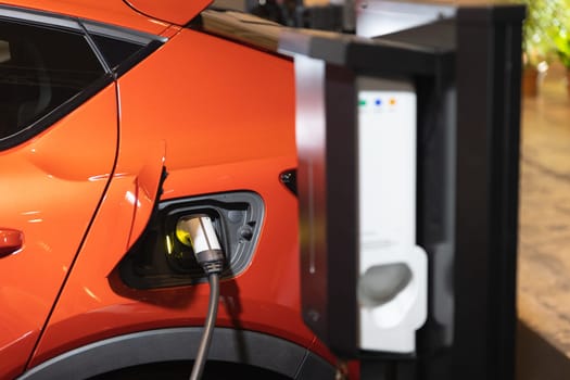 An orange electric car plugged in to a charging station