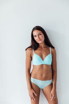 brunette woman in blue lingerie stands on a white background