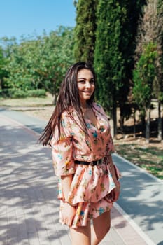 woman in a colored dress in motion in a park on a walkway