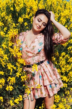 woman in a colored dress stands at the yellow flowers with her eyes closed