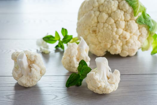slices of raw small raw cauliflower on a light wooden table
