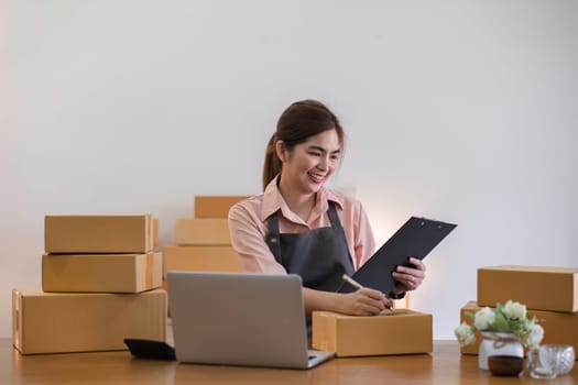 Portrait of starting a small business SME business owner Female entrepreneur working on merchandise boxes Receipts and checks online orders to prepare boxes for seller to customers..