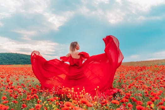 Happy woman in a long red dress in a beautiful large poppy field. Woman stands with her back in a long red dress, posing on a large field of red poppies.