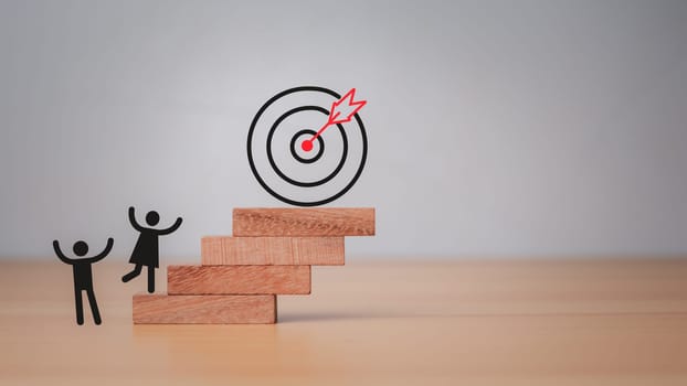 Company employees climb the square wooden steps to reach the dart board. It represents the concept of business strategy and target action plan.