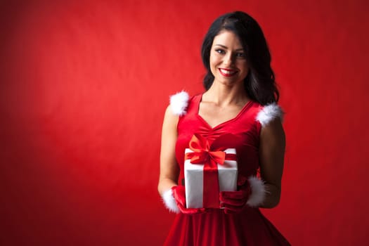 Beautiful woman in santa claus costume with christmas gift