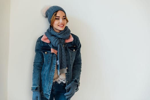 woman with a warm hat with a scarf in winter clothes stands on a white background