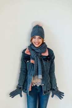 woman with a warm hat with a scarf in winter clothes stands on a white background