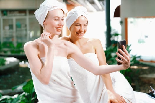 Couple of young beautiful women with beautiful skin in white towel taking a photo together at outdoor surrounded by peaceful natural environment. Beauty and healthy spa concept. Tranquility.