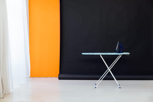 ironing board with iron on black orange background interior