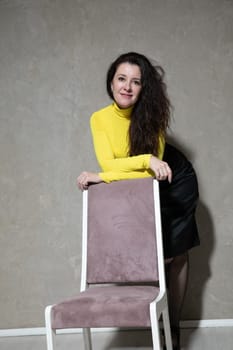 a beautiful woman stands by a pink chair in the office of a psychologist office worker