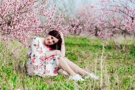 a beautiful woman sitting by a tree in pink flowers nature parks walk peach garden