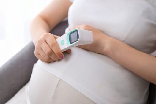 Pregnant woman holding a thermometer in her hand. Health care concept. Illness during pregnancy