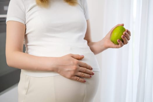 Pear in pregnant woman hands as a healthy eating concept.