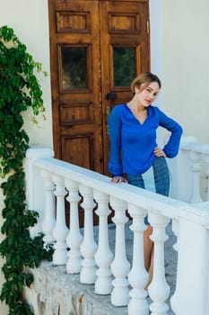 beautiful woman in blue clothes stands on the street at the door of the front door.