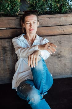 woman sitting against a wooden wall outside