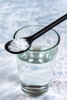 Spoon of baking soda over glass of water, isolated on white