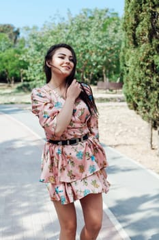 brunette in a dress in flower walks in the park rest walk