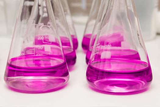 Flasks with liquid colored pink. Chemical analysis, organic test of water in the laboratory