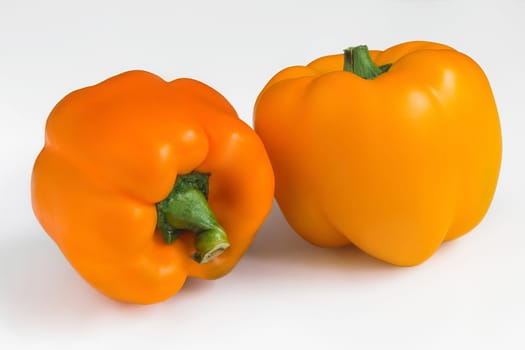 Two ripe orange peppers on a white isolated background