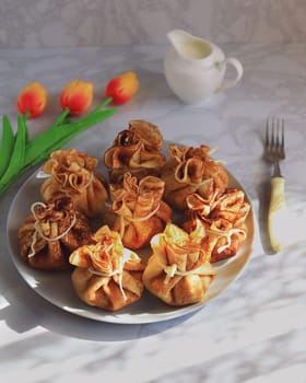 Serving the table for Maslenitsa with pancakes in the form of bags, milk and tulips