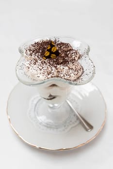 Dessert of sponge cake and whipped cream in a transparent cream bowl on the table