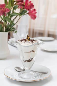 Dessert of sponge cake and whipped cream in a transparent cream bowl on the table