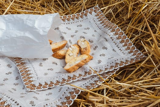 Almond cookies crackers with pieces of nuts fell out of a paper bag on a napkin lying on the straw