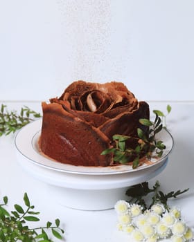 Chocolate cake in the form of a rose on a white background. A sweet treat for the holiday