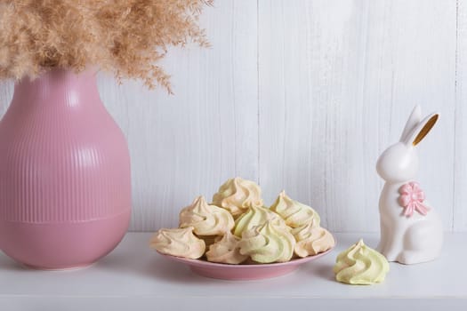 Festive light card with a porcelain rabbit, meringue and a pink vase with copy space