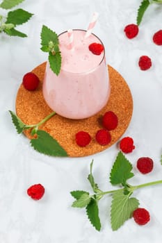 Milkshake with raspberries in a glass glass with melissa leaves in the design