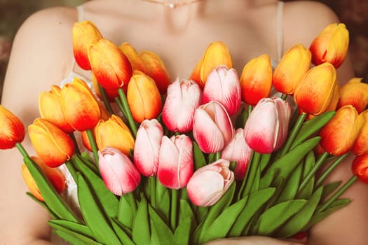 Young woman embraces a bouquet of tulips close-up without face selective focus