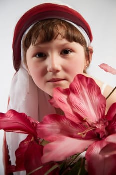 Portrait of Little girl in a stylized Tatar national costume with flowers on a white background in the studio. Photo shoot of funny young teenager who is not a professional model