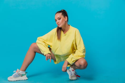 a woman in tracksuit sits on a blue background