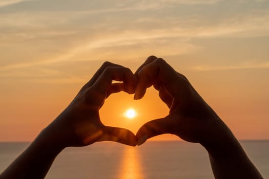 Hands heart sea sanset. Hands forming a heart shape made against the sun sky of a sunrise or sunset on a beach.