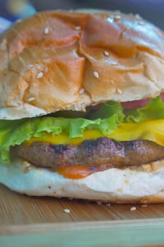 Cheeseburger With Salad And Tomato On a wooden board .