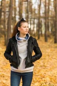 Outdoor atmospheric lifestyle portrait of young beautiful young woman copy space. Warm autumn fall season. Millennial generation and youth.