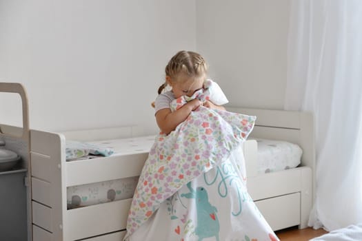 A girl makes a bed in the children room