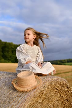 A girl sitting on a bale of wheat Countryside