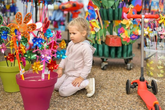 Girl looks at the colourful windmills in the store