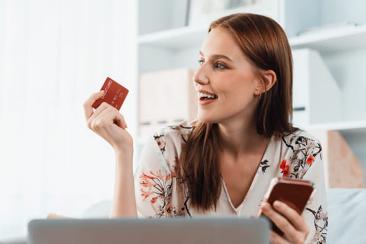 Young happy woman buy product by online shopping at home while ordering items from the internet with credit card online payment system protected by utmost cyber security from online store platform