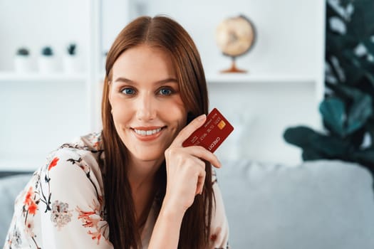 Young happy woman buy product by online shopping at home while ordering items from the internet with credit card online payment system protected by utmost cyber security from online store platform