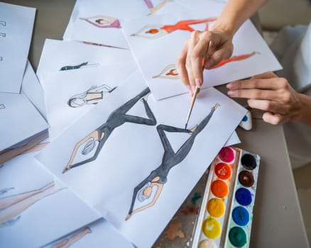 Faceless woman draws watercolor sketches of sportswear. Close-up of the hands of a fashion designer