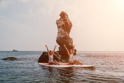 Woman sup yoga. Middle age sporty woman practising yoga pilates on paddle sup surfboard. Female stretching doing workout on sea water. Modern individual hipster outdoor summer sport activity