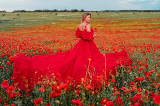 Woman poppy field red dress. Happy woman in a long red dress in a beautiful large poppy field. Blond stands with her back posing on a large field of red poppie