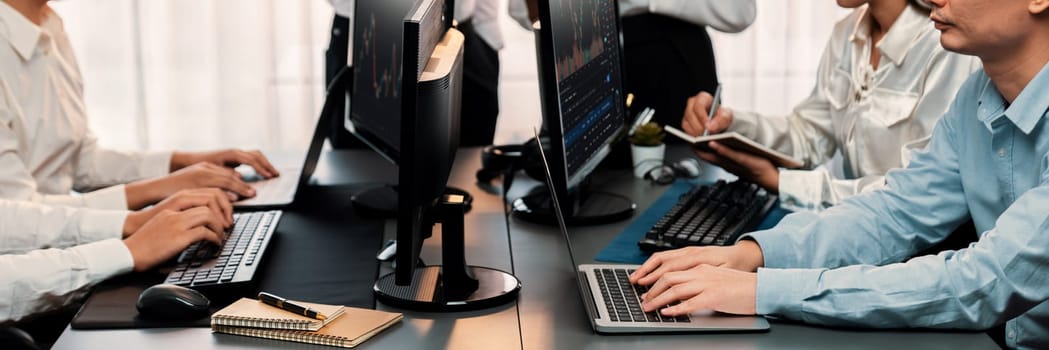 Group of traders discussing on office desk, monitoring stock market on monitor at office workplace. Businessman and broker analyzing stock graph together at stock trading company. Trailblazing