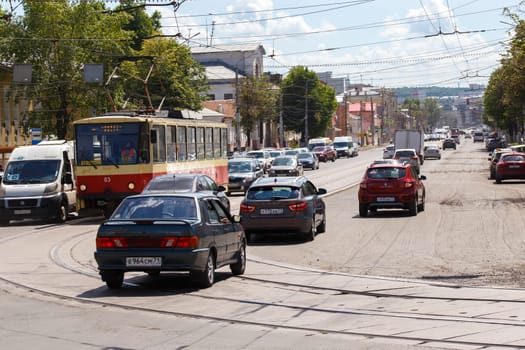 cars and tram driving along summer day street road in Tula, Russia - June 14, 2021