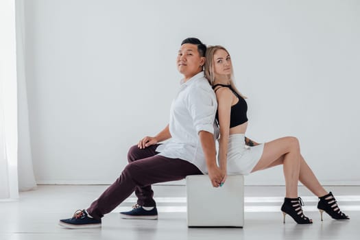 a woman and a man sit with their backs to each other in a bright room