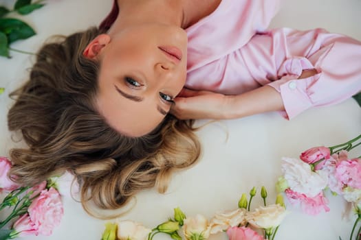 a beautiful blonde lies in flowers in the room